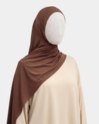Hijab jersey modal marron café porté de profil, drapé fluide sur l'épaule, tissu souple et respirant